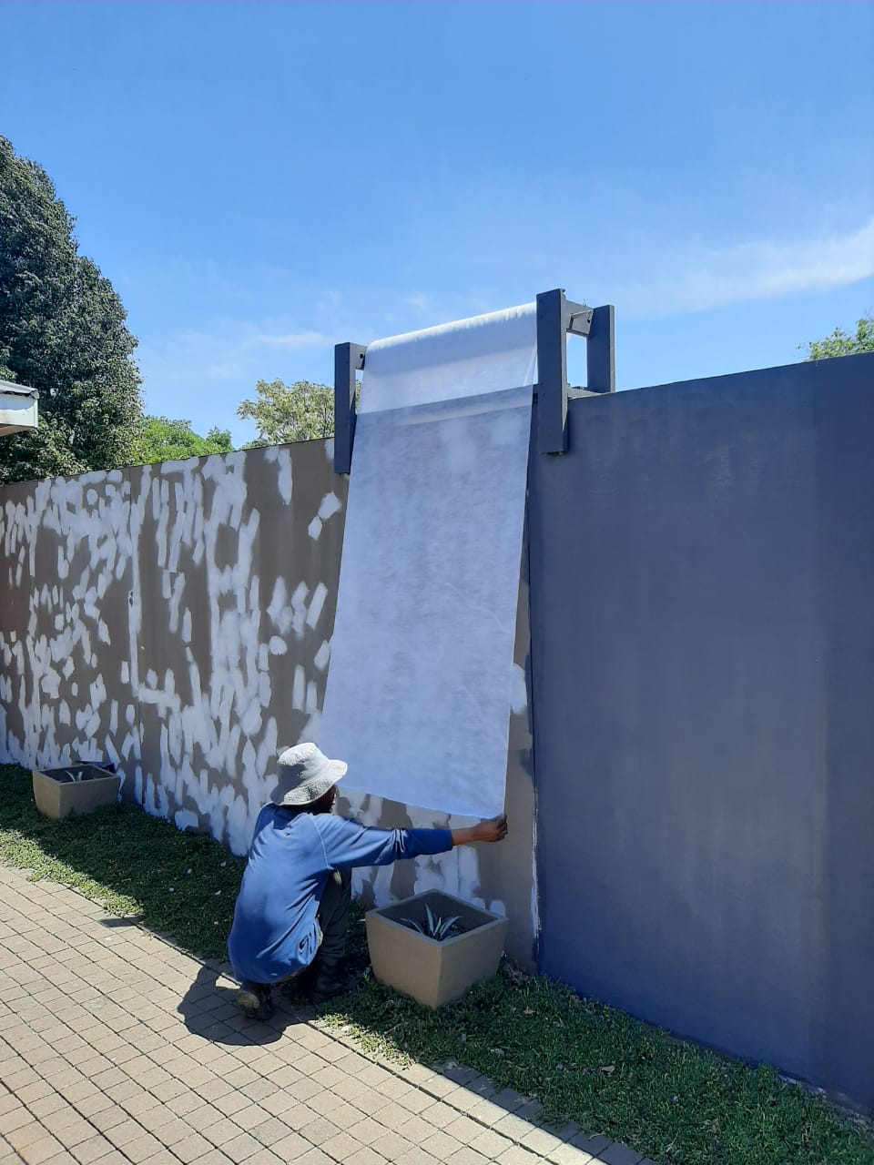 A worker applying a white waterproofing membrane to the wall